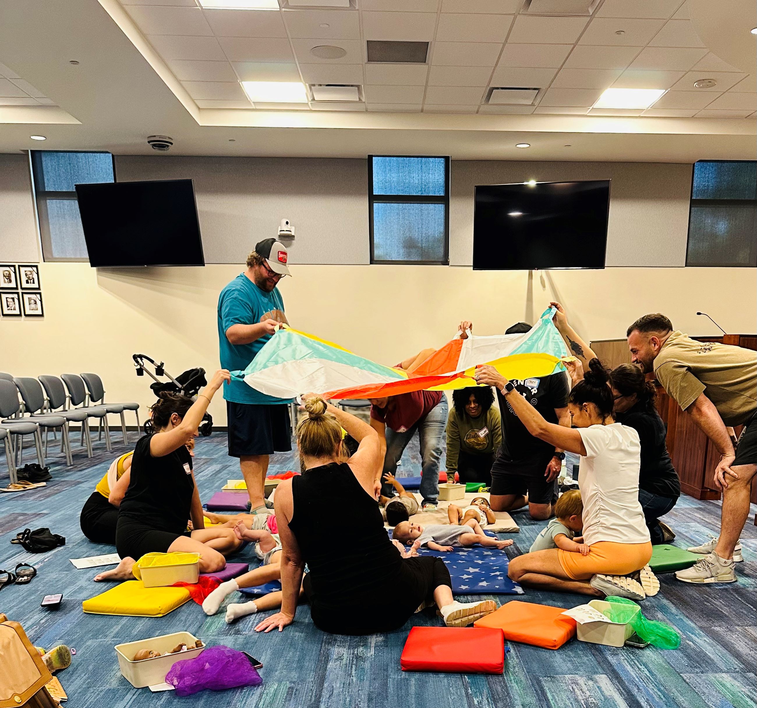 Parents/guardians sitting on floor with infants signing songs